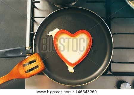 Pancake in form of heart is cooked in the pan