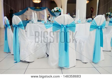 Beautiful fabric bow on the chair. Wedding restaurant for marriage. White decor for bride and groom. Colorful decoration for celebration. Beauty bridal interior
