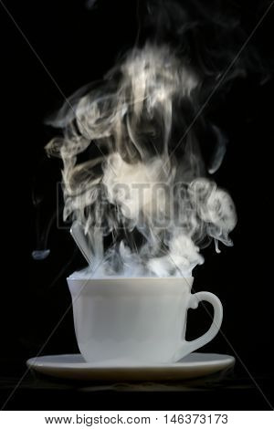 white cup with hot liquid and steam on black