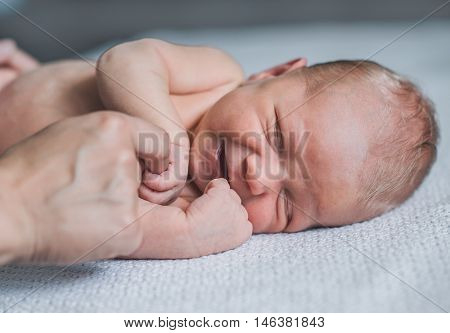 Sweet smiling newborn baby lying in bed.