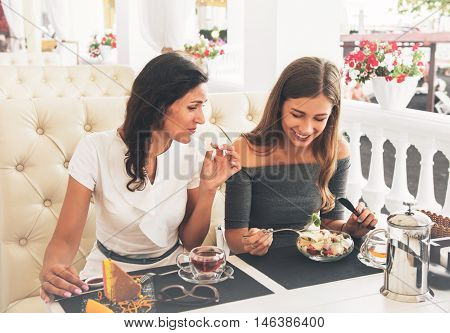 Portrait of teenage daughter and her mother having lunch together at the street cafe.