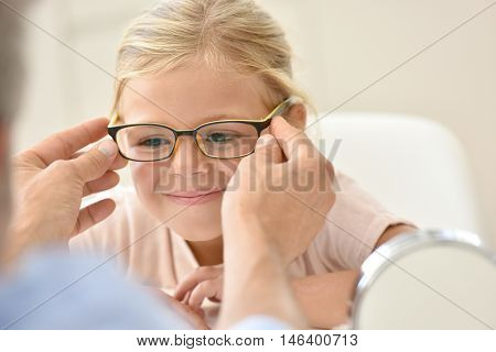 Little girl at the optician trying different eyeglasses 