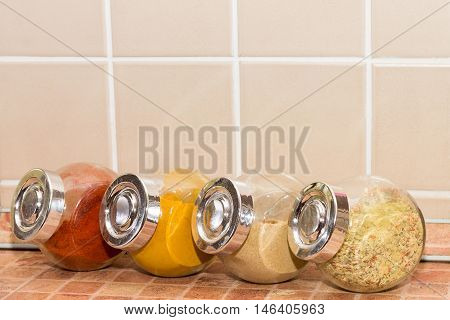 Four different spices in jars: paprika, garlic, turmeric and mixed one.