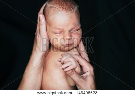 Newborn baby boy sleeping in mother's hands