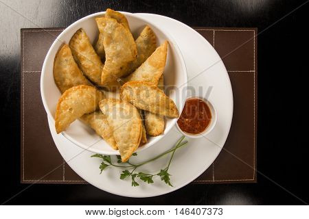 Meat pastel portion served with sauce.. Traditional Brazilian snack.