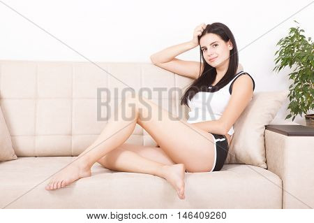 Relaxing woman sitting comfortable in sofa lounge chair smiling happy looking at camera. Resting beautiful young multicultural asian caucasian girl in her 20s .