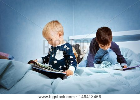 Brothers sitting in the bed in pyjamas and reading books