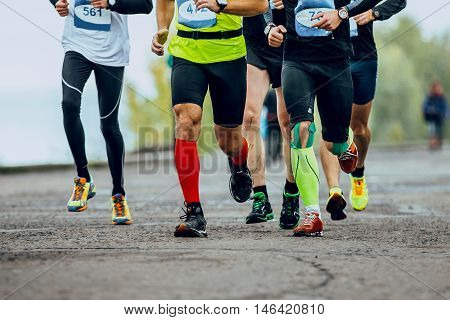 group of men runners running streets of city. legs compression socks. competition in marathon
