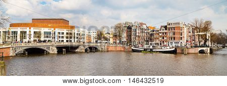 Amsterdam, Netherlands - April 2, 2016: Traditional old buildings, Opera house, canal, bridge panorama in Amsterdam, Netherlands