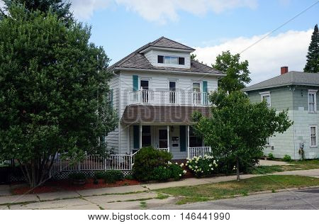 PETOSKEY, MICHIGAN / UNITED STATES - AUGUST 5, 2016: An elegant Victorian home, with a wraparound front porch a balcony, and a white picket fence, near downtown Petoskey.