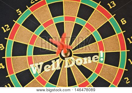 Text Well Done written on the circular target with a plastic feather in the center