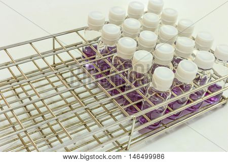 Chemical bottle with purple chemical in steel rack