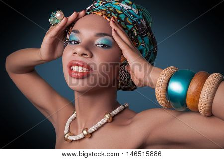 young beautiful fashion model with traditional african style with scarf, earrings and makeup on dark blue background.
