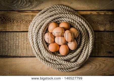 Eggs in a basket made from rope on a wooden table