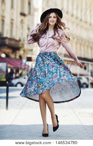 Outdoor full body portrait of young beautiful fashionable happy lady posing on street of the old city. Model wearing stylish hat and clothes. Girl looking at camera. Female fashion. City lifestyle