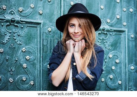 Close up street portrait of cute young smiling happy lady wearing stylish wide-brimmed hat. Model looking at camera. City lifestile.