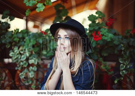 Portrait of beautiful surprised girl. Colorful background. Model wearing stylish black hat. Lady looking up
