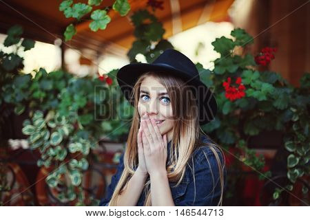 Portrait of beautiful surprised girl. Colorful background. Model wearing stylish black hat. Lady looking at camera