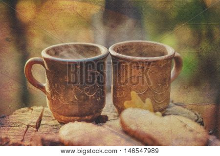 Two Clay Rural Cup with Hot Beverage are on the Wooden Stumb with Autumnal Leaves.Nature Background.Selective Focus.Toned