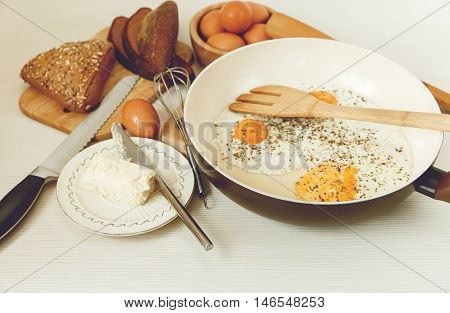 Fried Eggs in the Frying Pan,Breakfast Ingredients.Orange,Bread,Butter.Kitchen Accessories.Cooking Morning Food.Selective Focus