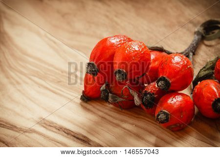 Hawthorn on wooden rustic table background. Rose hips haw fruit of the dog rose.