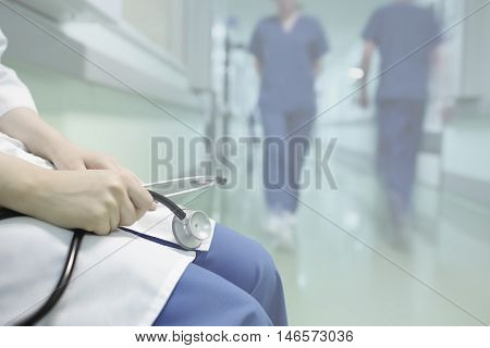 Medical doctor sitting in hospital corridor holding a stethoscope