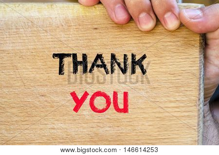 Human hand over wooden background and thank you text concept