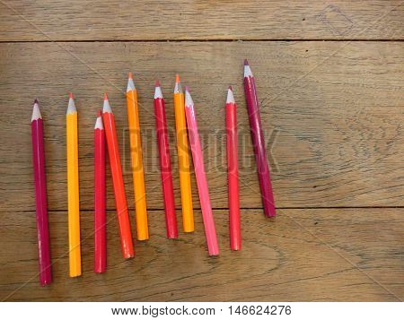 Set of the red to yellow color pencil on the wood table with ligthing