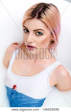 Attractive sexy woman with wet body and hair relaxing in  water, looking at camera
