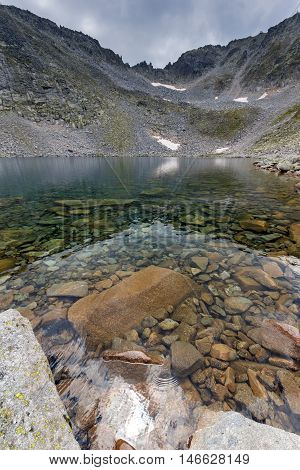Clear waters of Ledenoto (Ice) Lake and clouds over Musala Peak, Rila mountain, Bulgaria