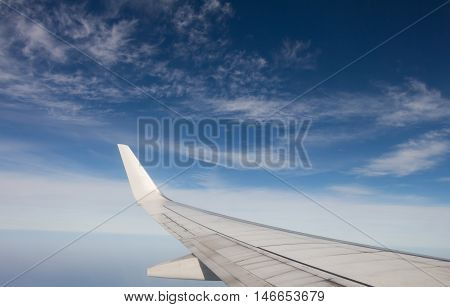 Wing of airplane flying above the clouds in the sky