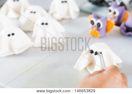Confectioner working on the figures of Halloween with fondant paste