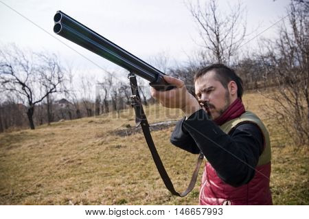 Hunter with barrel aiming bird , pointing gun up