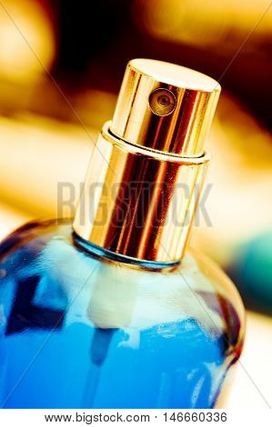 Gold atomizer atop translucent blue perfume bottle