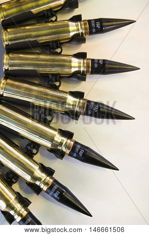 A view of a series of high caliber FAP bullet mounted on an ammunition belt for use in a machine gun.