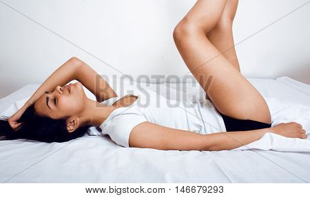 pretty indian brunette real woman in bed smiling, white sheets, tann skin close up . cant sleep, fooling around