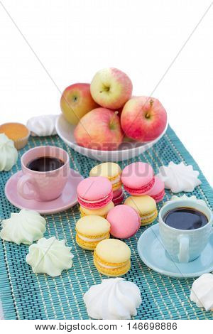 Still life of served coffee cups macaroon cookies marshmallows and apples