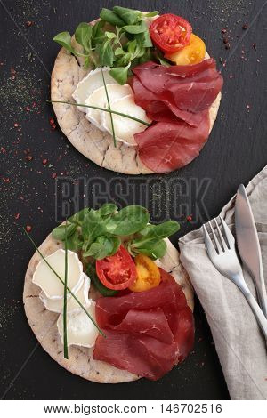 Swedish flatbread hallakaka with sliced ham, Sainte Maure cheese, tomato and lettuce