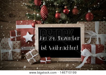 Nostalgic Card For Seasons Greetings. Christmas Tree With Balls And Snowflakes. Gifts In Front Of Wooden Background. Chalkboard With German Text Am 24. Dezember Ist Weihnachten Means Merry Christmas