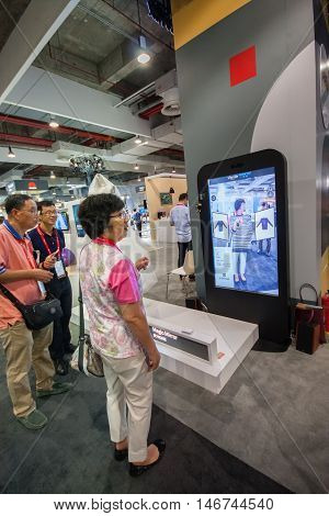 SHANGHAI CHINA - SEPTEMBER 2 2016: Attendees of Huawei Connect 2016 information technology conference test virtual fitting room simulator at exhibition hall in Shanghai China on September 2 2016.