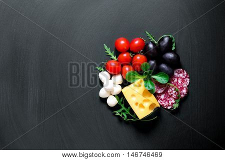 Pizza ingredients concept with empty space on a blackboard for a text or drawing