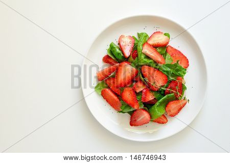 Spinach and strawberry salad with poppy seeds and vegetable oil dressing, top view
