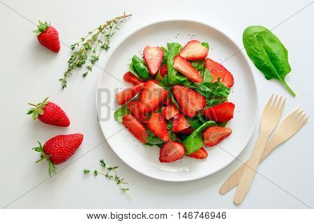 Spinach and strawberry salad with poppy seeds and vegetable oil dressing healthy and refreshing vegetarian dish top view