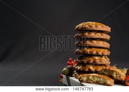 Typical Dutch filled spicy cookies with almonds on autumn colored and dark background