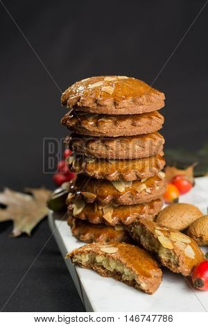 Typical Dutch filled spicy cookies with almonds on autumn colored and dark background