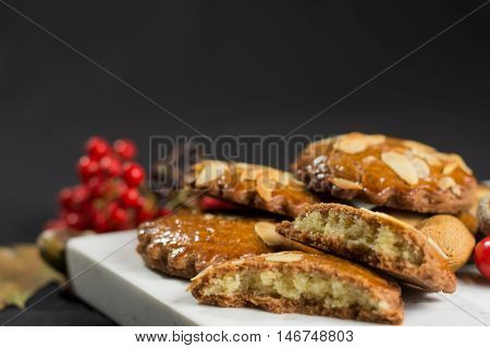 Typical Dutch filled spicy cookies with almonds on autumn colored and dark background