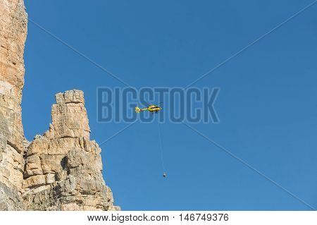 Medical rescue helicopter flying rescue injured climber on the Tre Cime. Italy, Dolomites