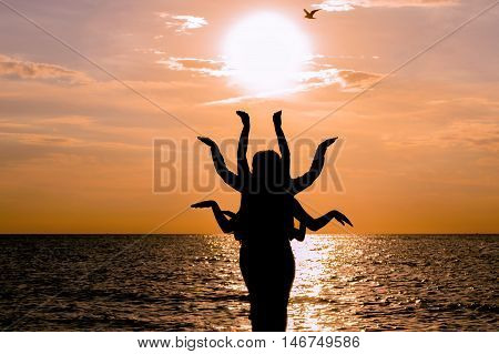 Indian dance silhouette on beautiful beach during sunset. Silhouette of human figure with many arms