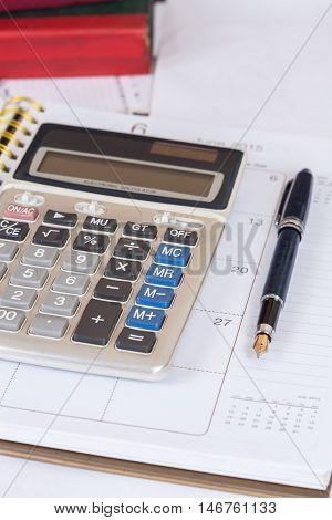 calculate and pen on calendar book on table