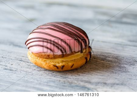 Cookie with pink glaze. Decorated biscuit on wooden surface. Bush cake with custard. New dessert in local cafe.